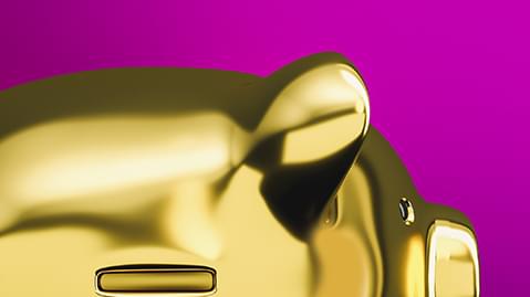 Close up of gold piggy bank in front of pink background